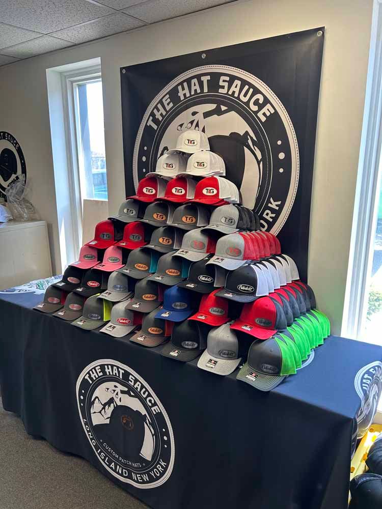 A table with a lot of hats on it and a sign that says the hat sauce