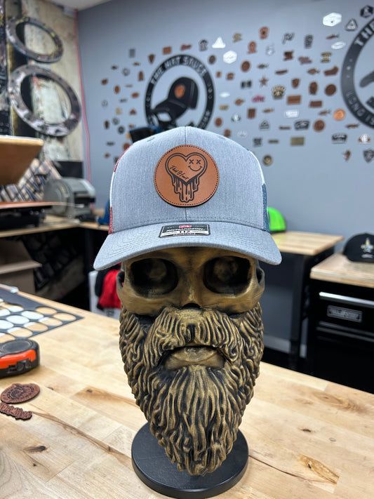 A skull with a beard is wearing a hat on a wooden table.