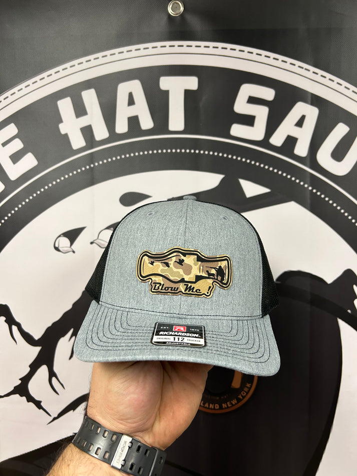 A person is holding a hat in front of a sign that says e hat sau