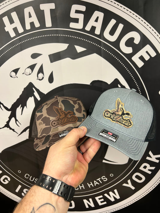 A person is holding a hat in front of a hat sauce logo