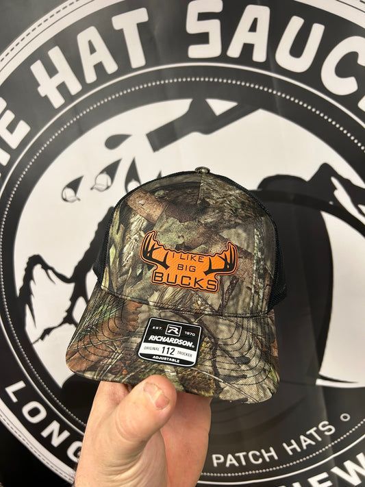 A person is holding a hat in front of a patch hats logo