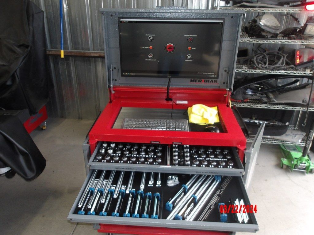 Red tool chest with open lid and drawers full of sockets and wrenches in a workshop.