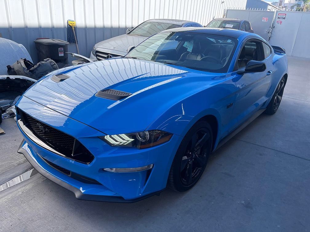 Blue sports car parked outdoors in an industrial lot, front-left view