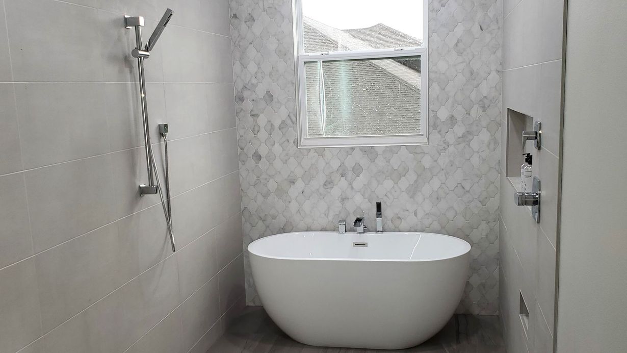 Modern bathroom with a white vanity, a toilet, and a glass-enclosed shower with marble-style walls and dark floor tiles.