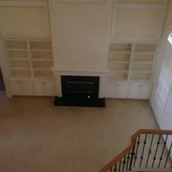 Built-in white bookshelves on either side of a fireplace with a black surround, viewed from above.