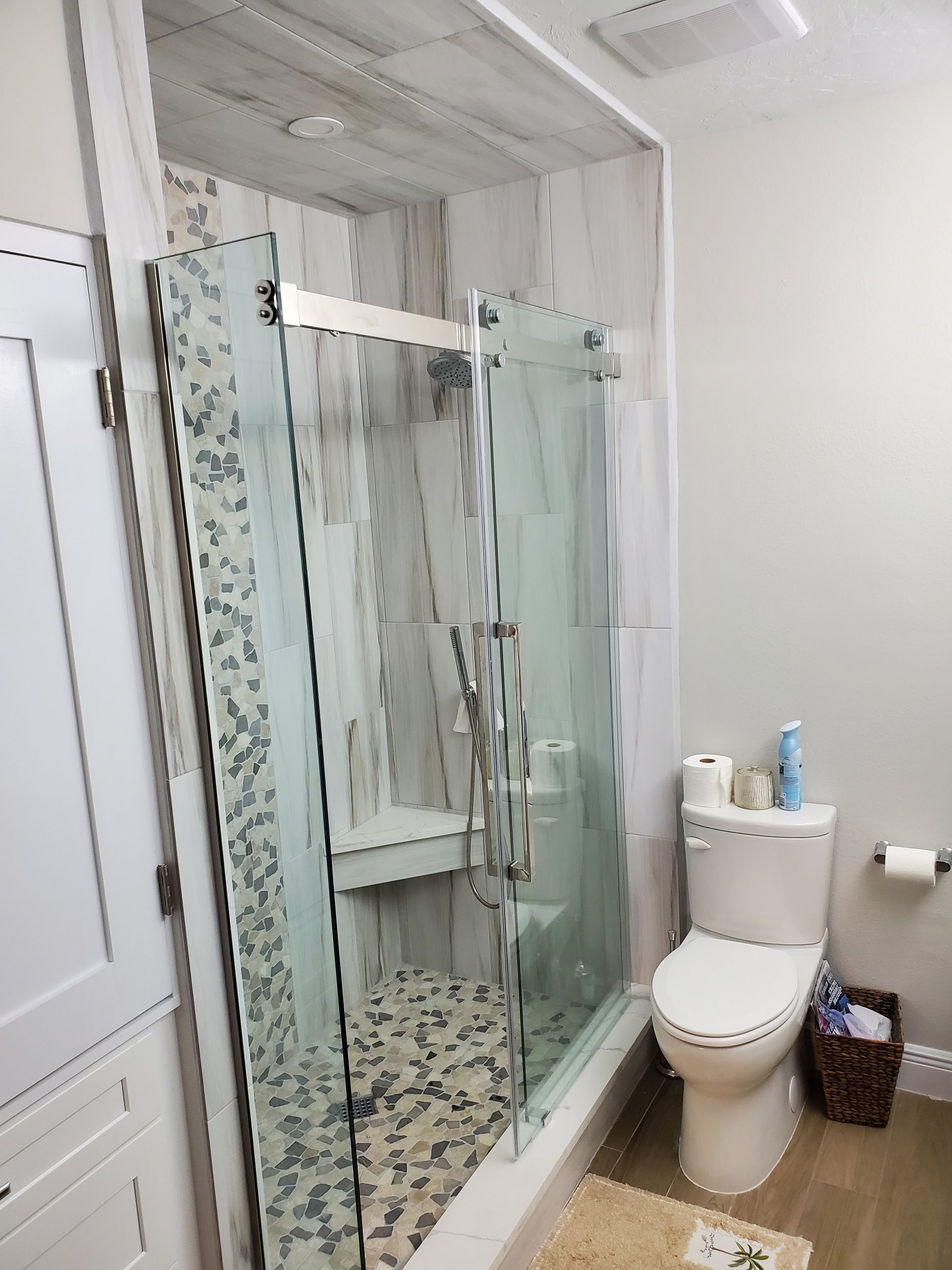 Modern bathroom featuring a glass-enclosed shower with tiled floors next to a white toilet.