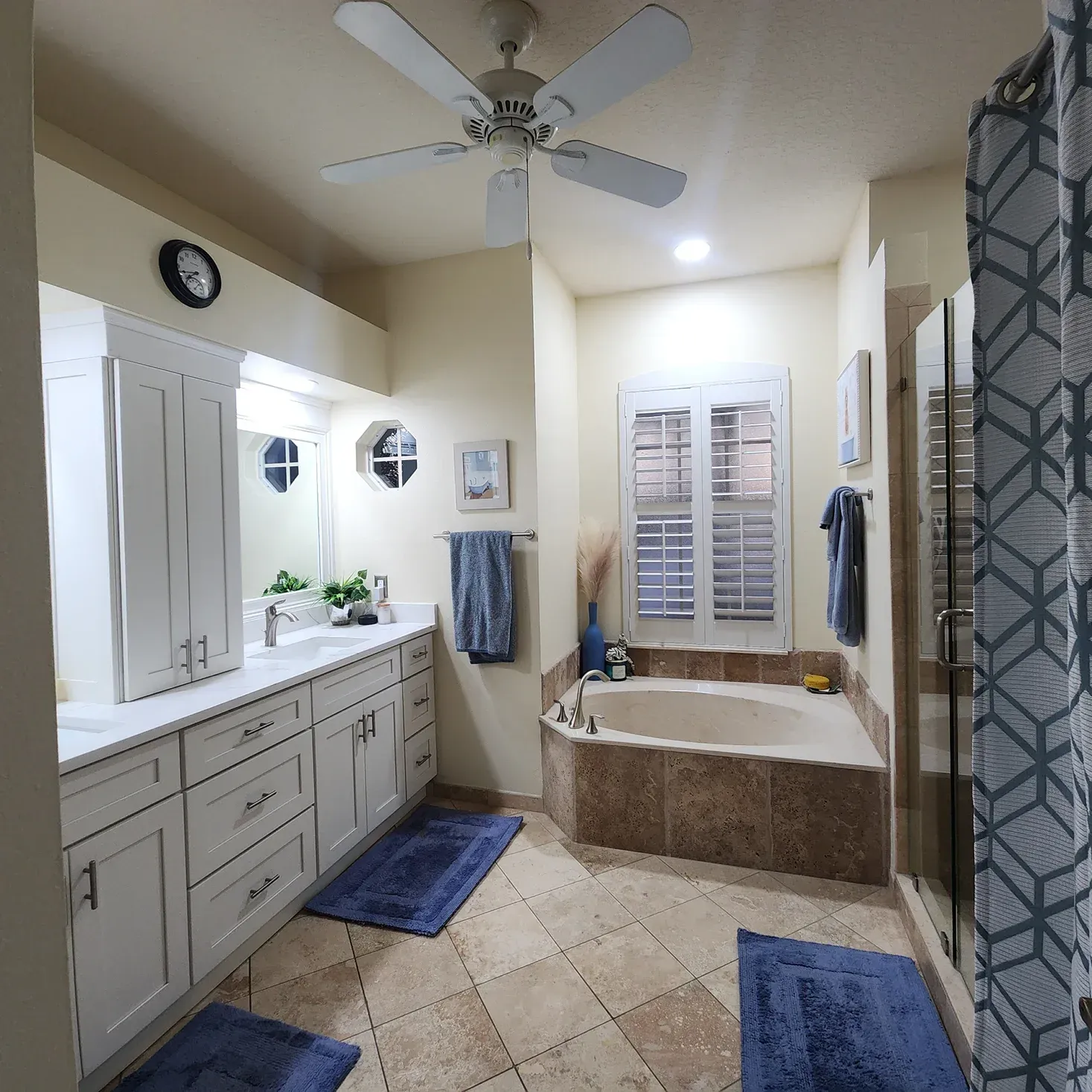 Bathroom with white cabinetry, blue accents, bathtub, shower, and ceiling fan.