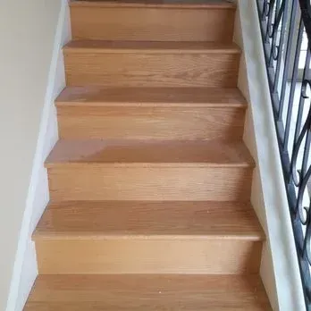 Wooden staircase with light brown treads and white risers, viewed from the bottom.