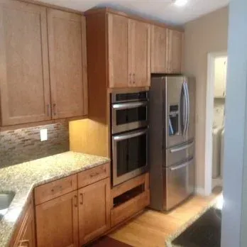 Kitchen with wood cabinets, granite countertop, stainless steel appliances, and door leading to a hallway.