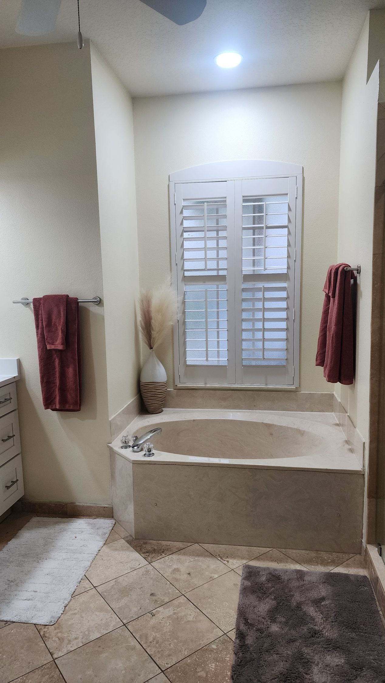 Modern bathroom with white soaking tub, shower, and toilet. Gray tile walls and floor.