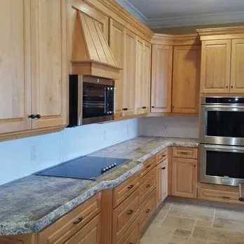 Kitchen with light wood cabinets, granite countertops, and stainless steel appliances.