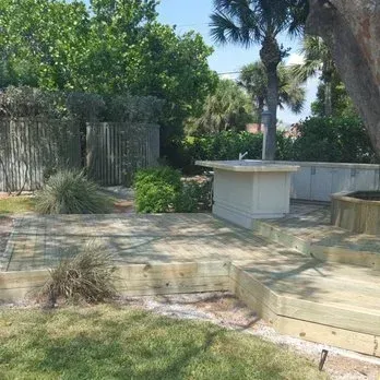 Wooden deck with landscaping and an outdoor kitchen.