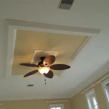 Ceiling with recessed area and ceiling fan. Beige ceiling with white trim, fan with light.