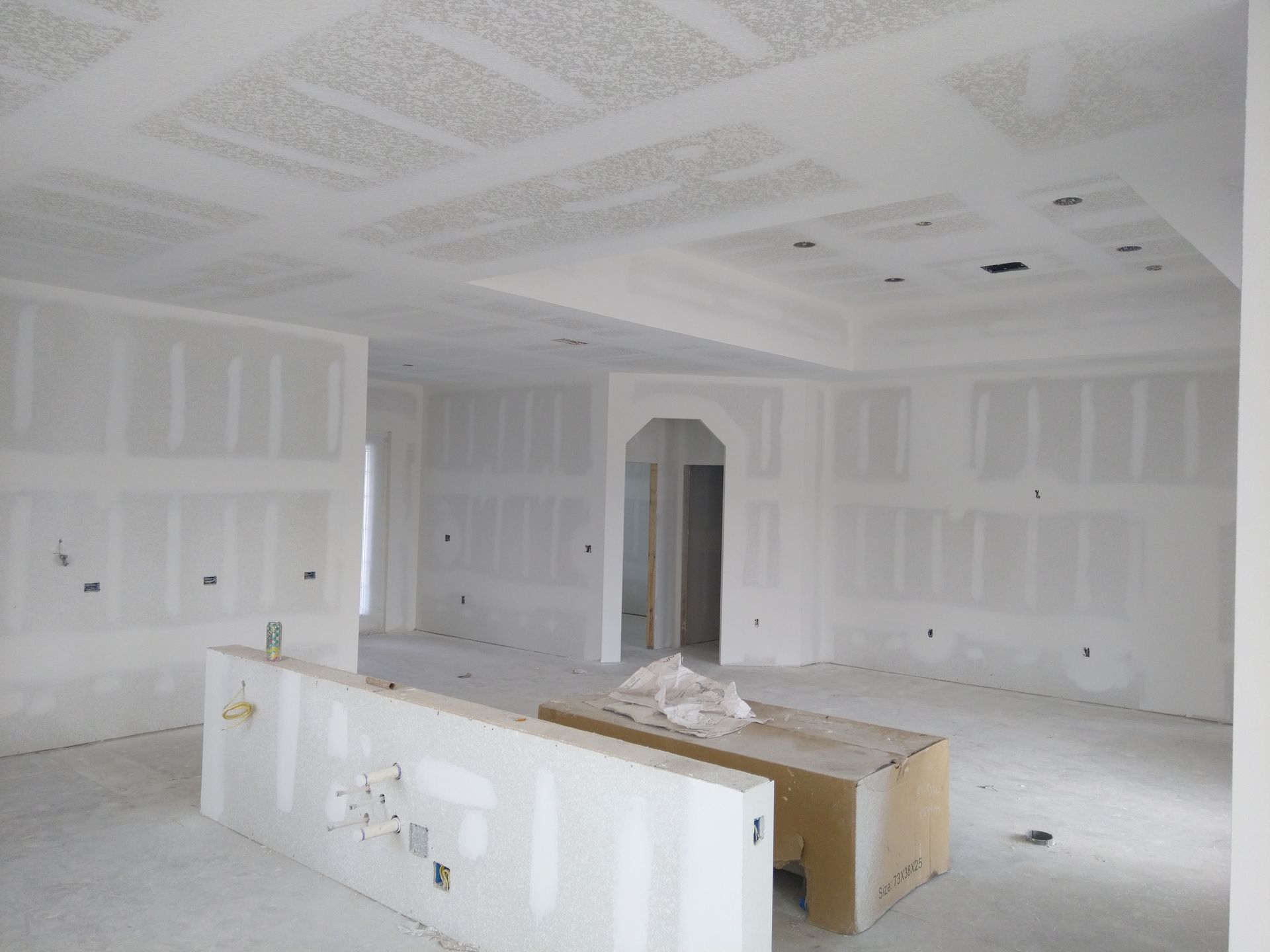 An unfinished interior room with drywall installed on walls and a textured ceiling, featuring an open floor plan.