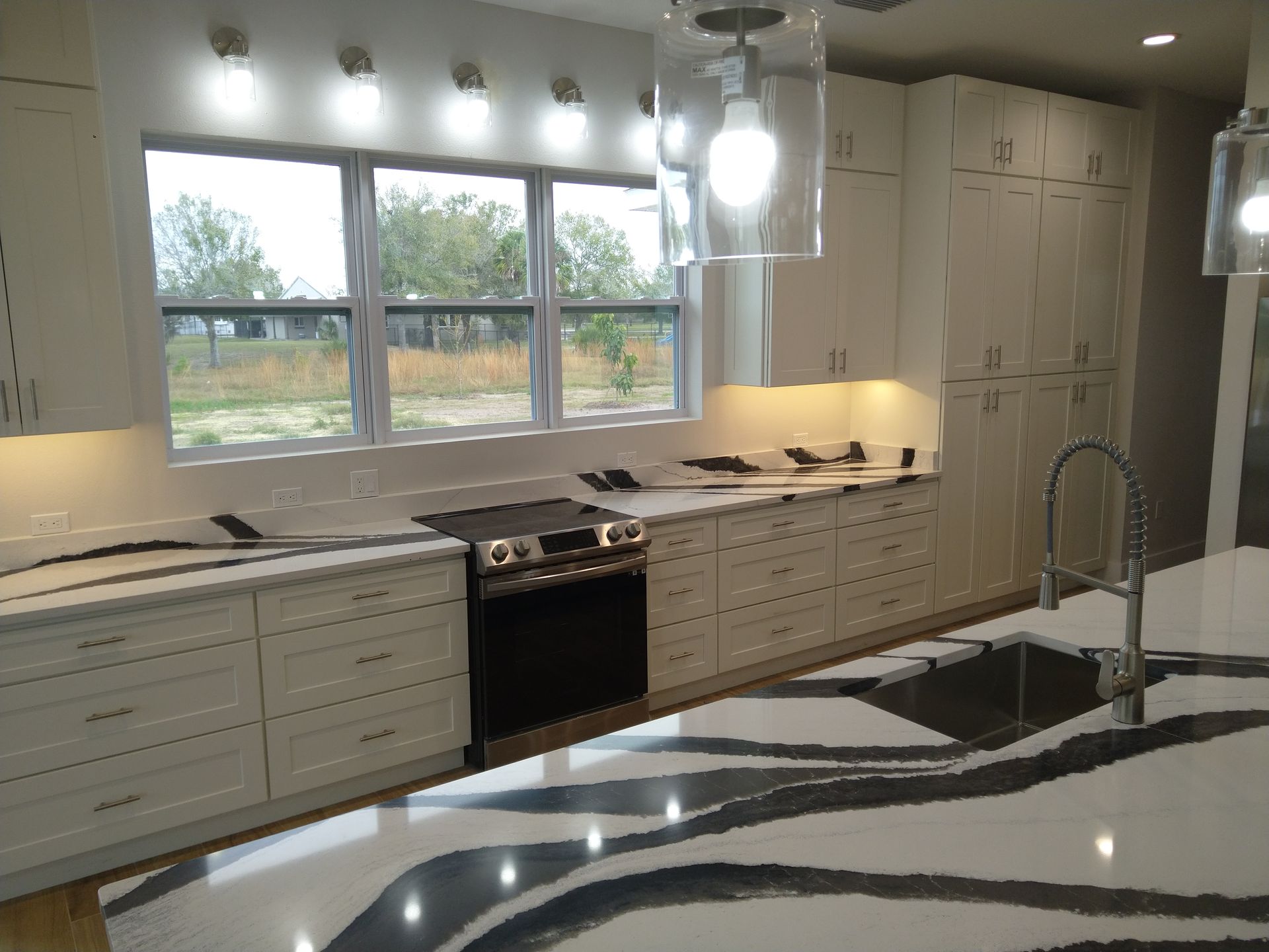 Modern kitchen featuring white cabinets, a black stove, and a white countertop with bold black veining patterns.