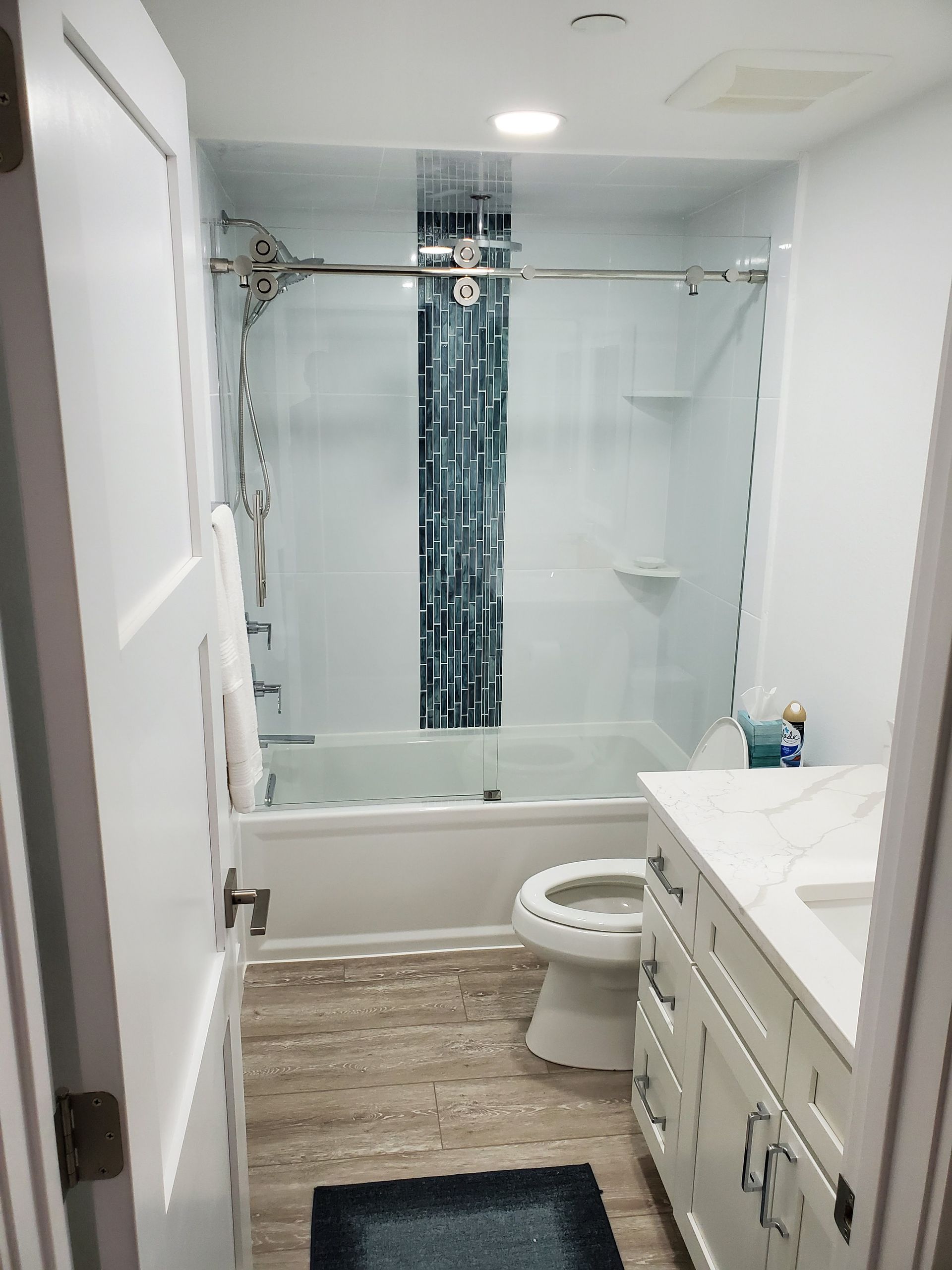 A bright bathroom featuring a white vanity, a toilet, and a bathtub with a blue-patterned shower curtain.