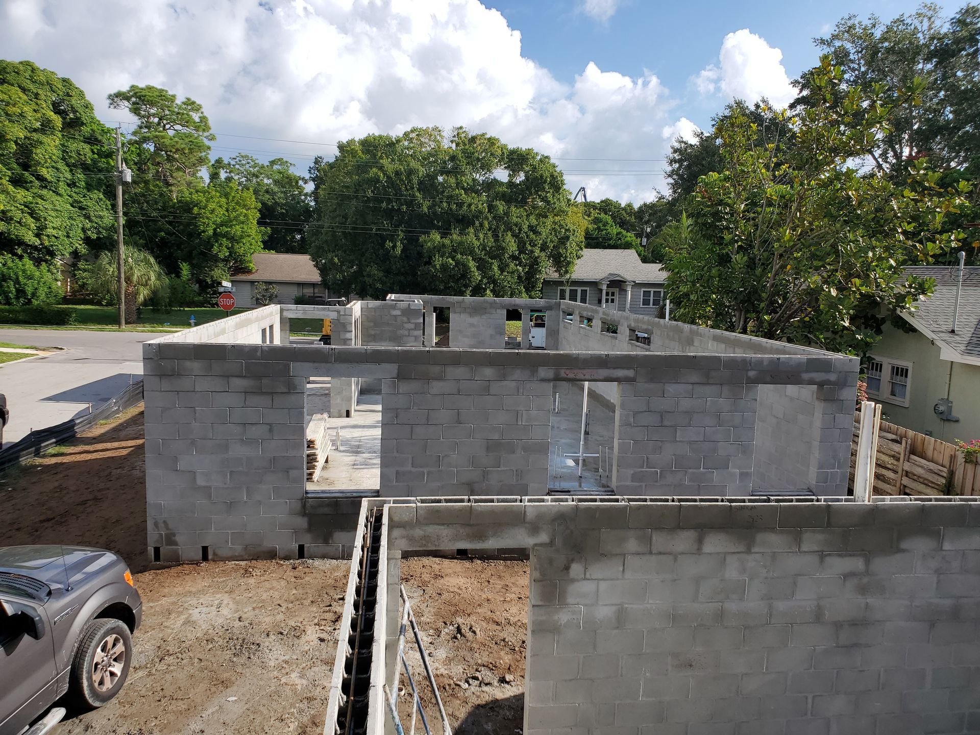 Construction site showing the partially built concrete block walls of a new residential house on a sunny day.