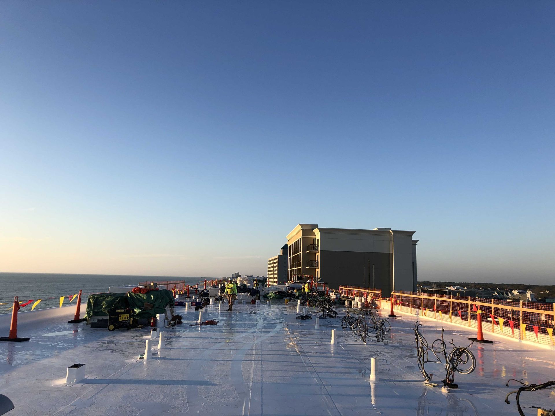 Snowy rooftop at sunset with parked cars and a building in the distance