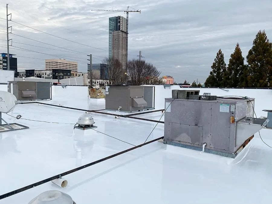 Snow-covered rooftop with HVAC units and a distant high-rise under construction