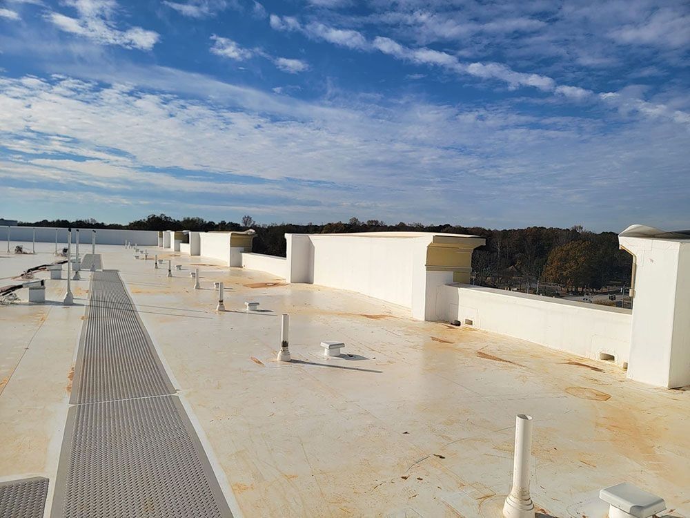 Rooftop with white walls and vents under a blue, partly cloudy sky