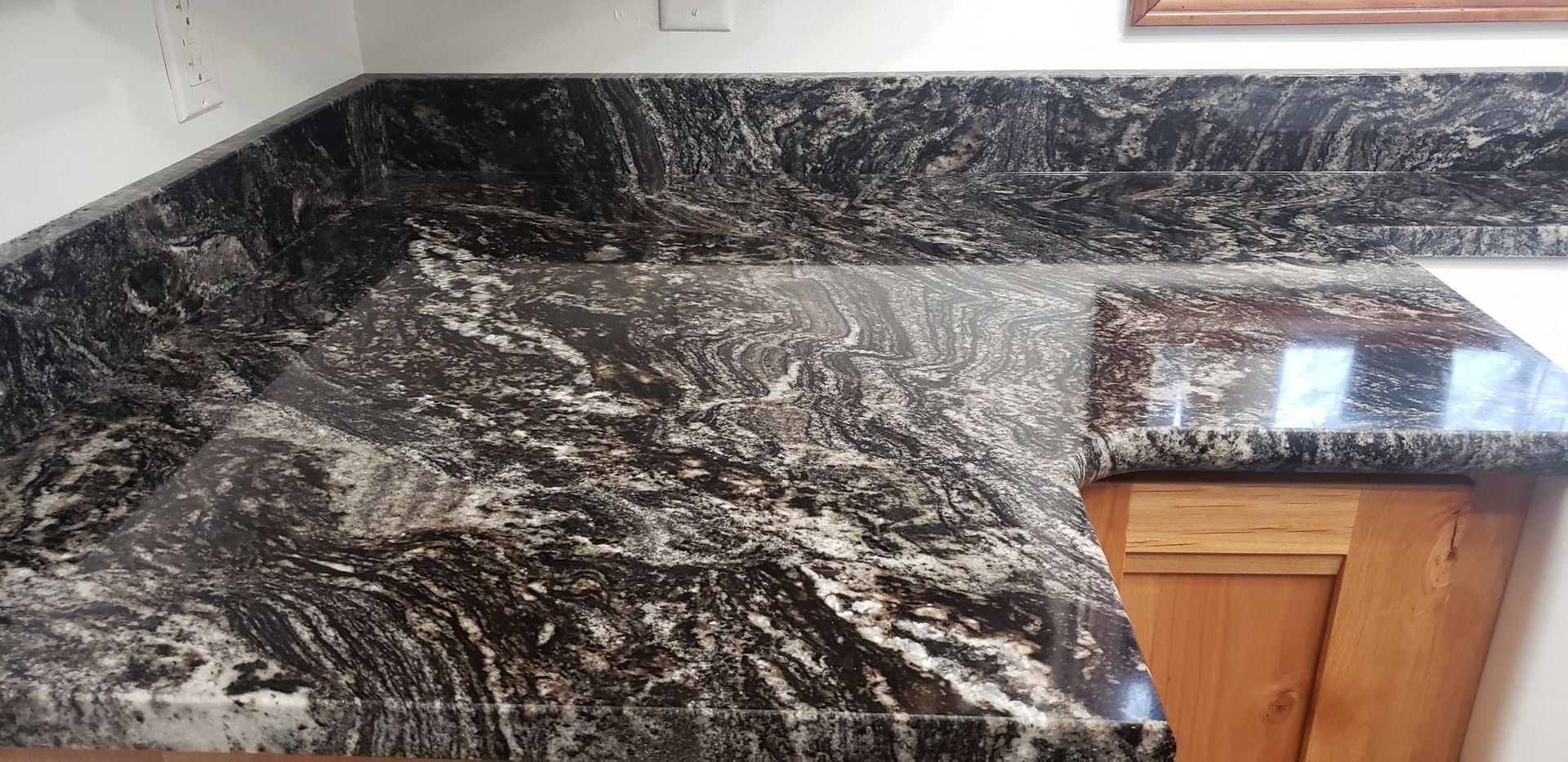 Black granite countertop with white and gray veining. Wooden cabinets below.