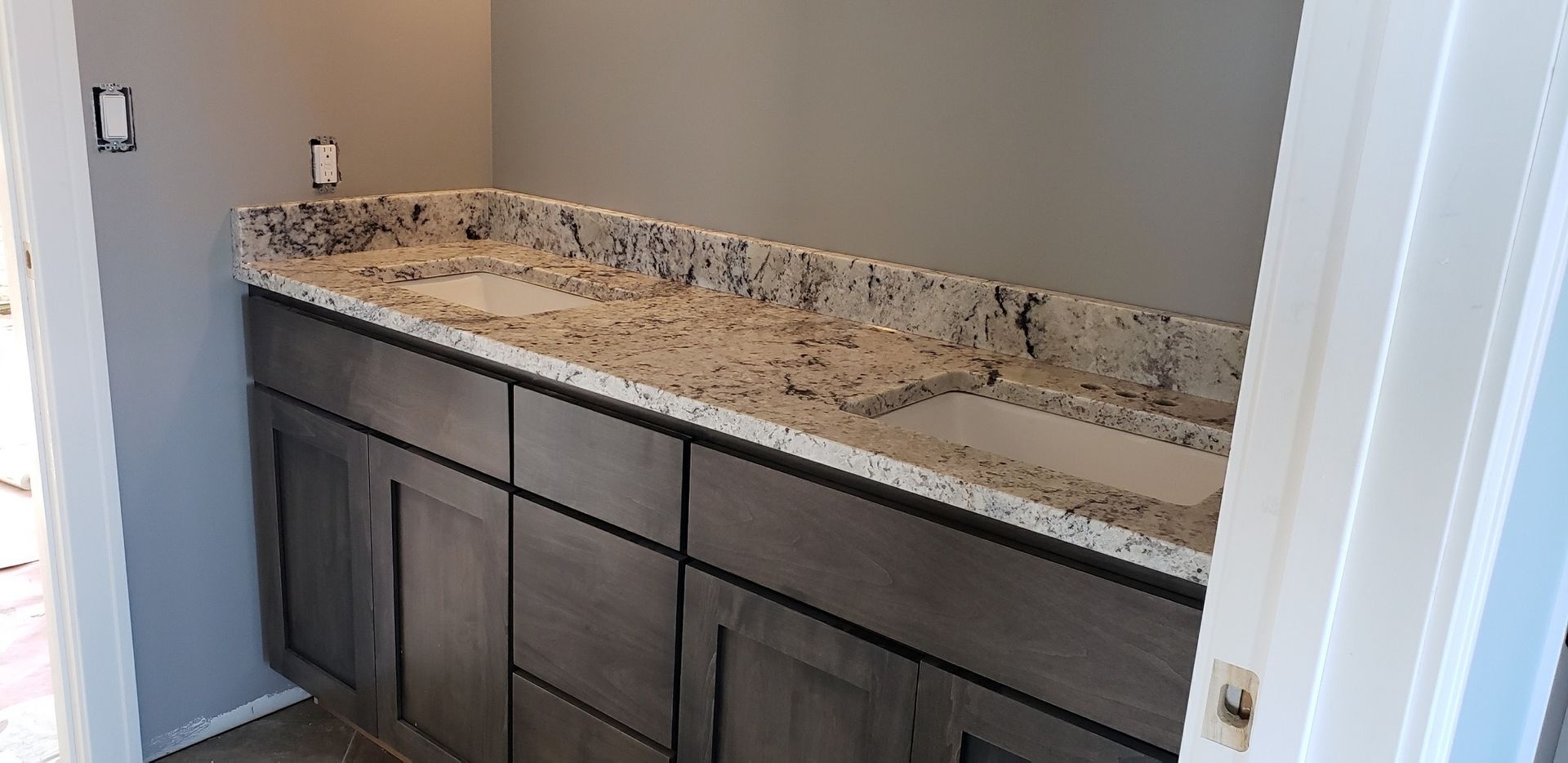 Bathroom vanity with a granite countertop and gray cabinets.