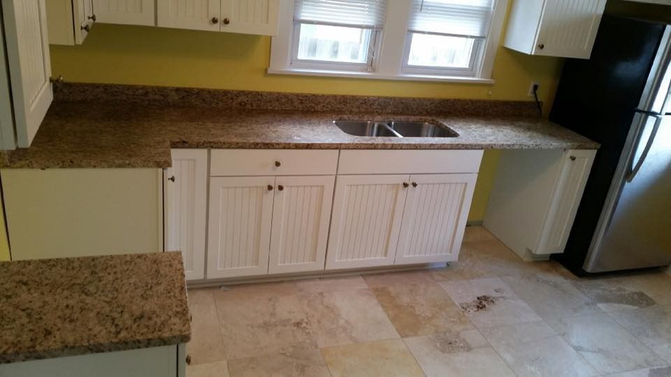Kitchen with white cabinets, granite countertops, double sink, and a refrigerator.