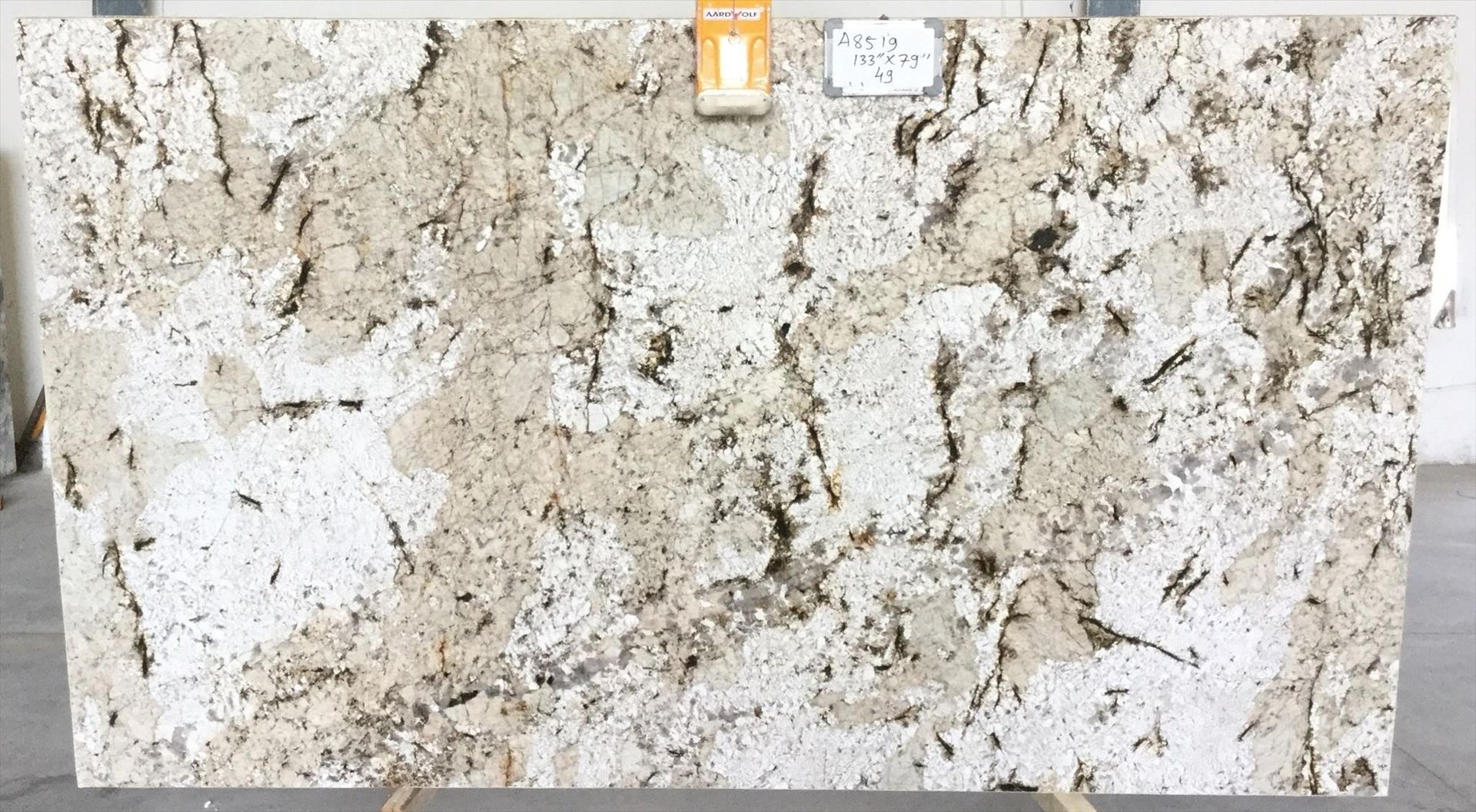 Large granite slab with white, beige, and gray mottled patterns on display.