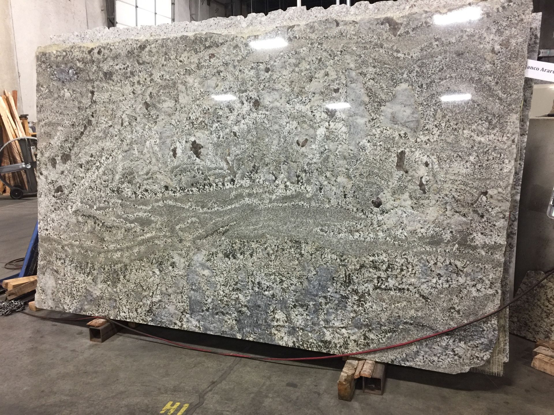 Large slab of granite with gray, white, and brown patterns, resting on a wooden pallet.