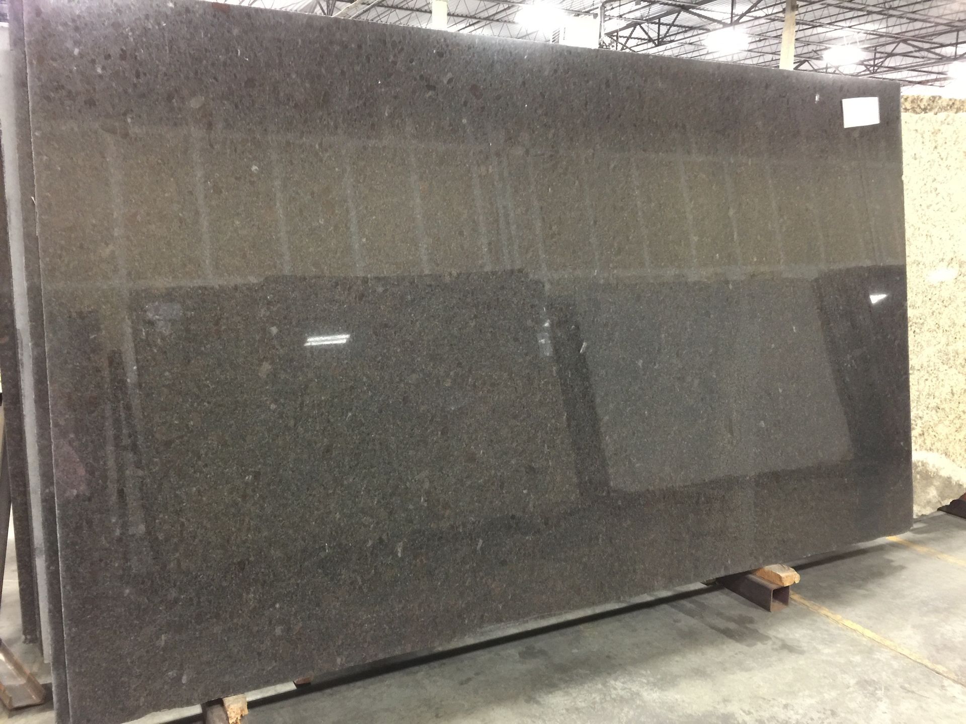 Large slab of dark granite stone in a warehouse setting.