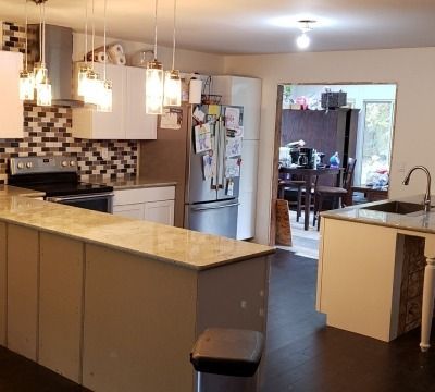 Modern kitchen with white cabinets, island, stainless steel appliances, and a mosaic backsplash.
