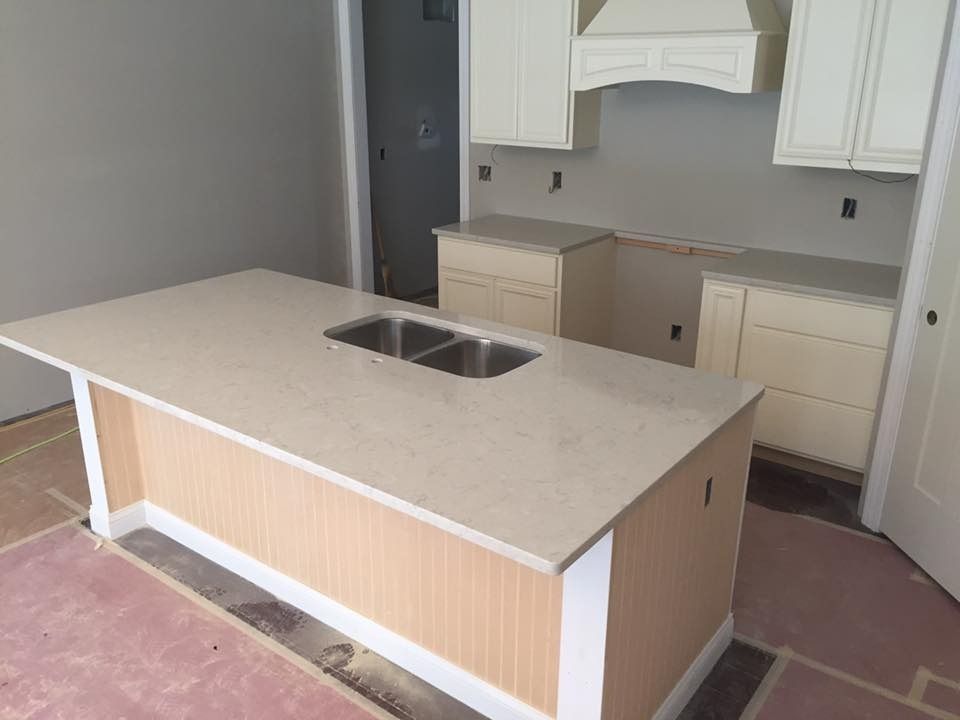 New kitchen under construction, light cabinets, island with sink, neutral countertops and walls.