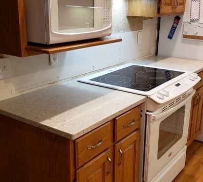 Kitchen with white appliances, wooden cabinets, and a gray countertop.