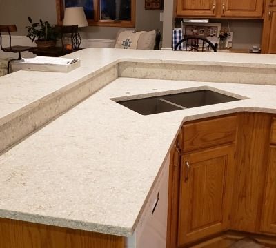 Light-colored kitchen countertops with a sink and wooden cabinets.