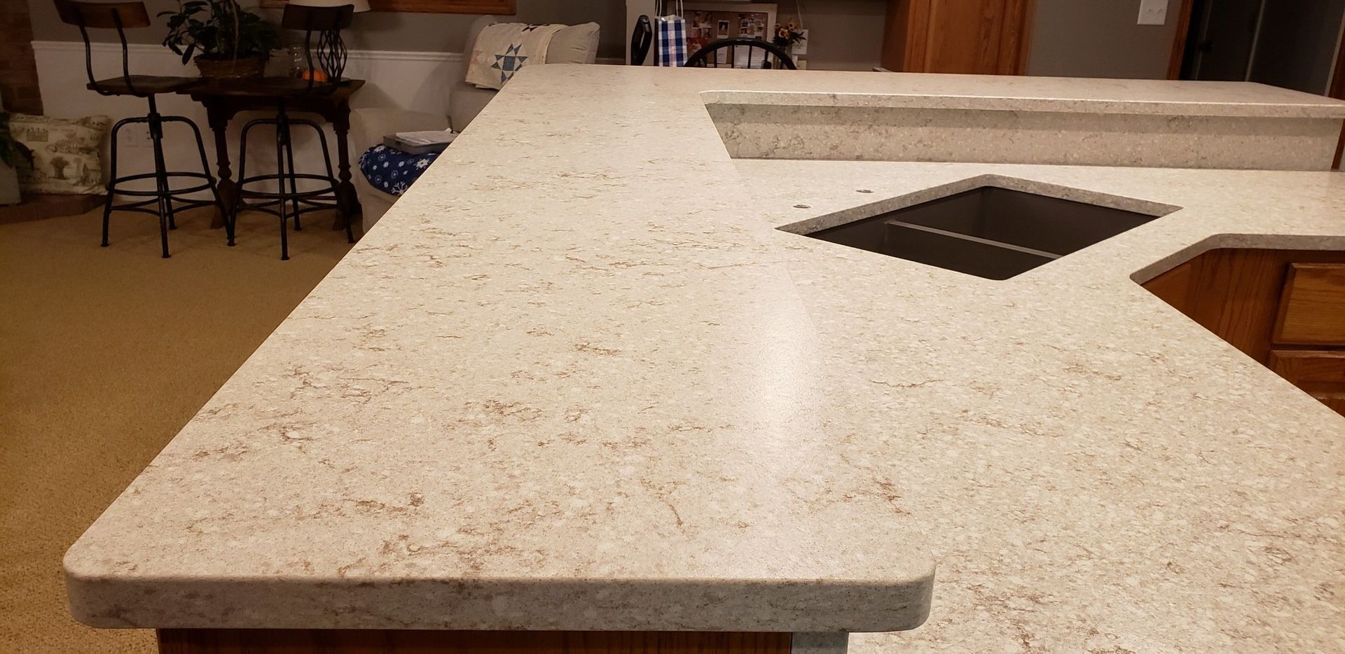 A kitchen with a light-colored countertop with an inset stove and a raised countertop area.
