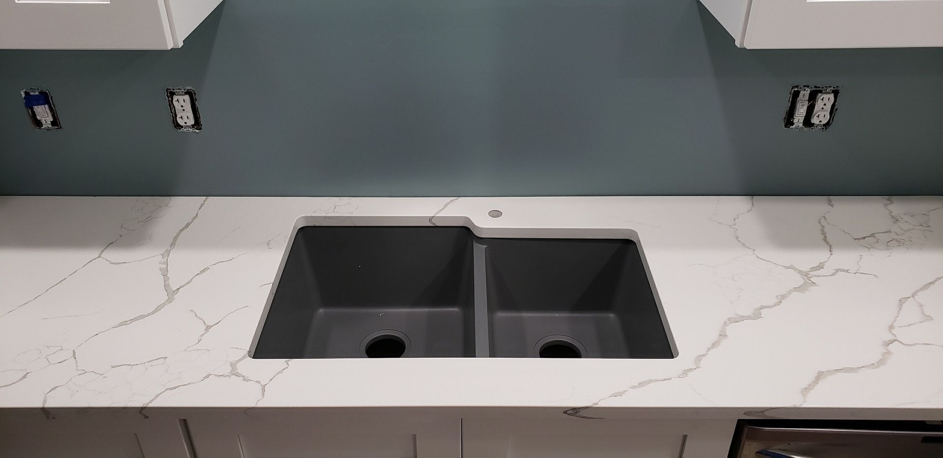 Kitchen with white countertops, a double basin sink, and blue wall.