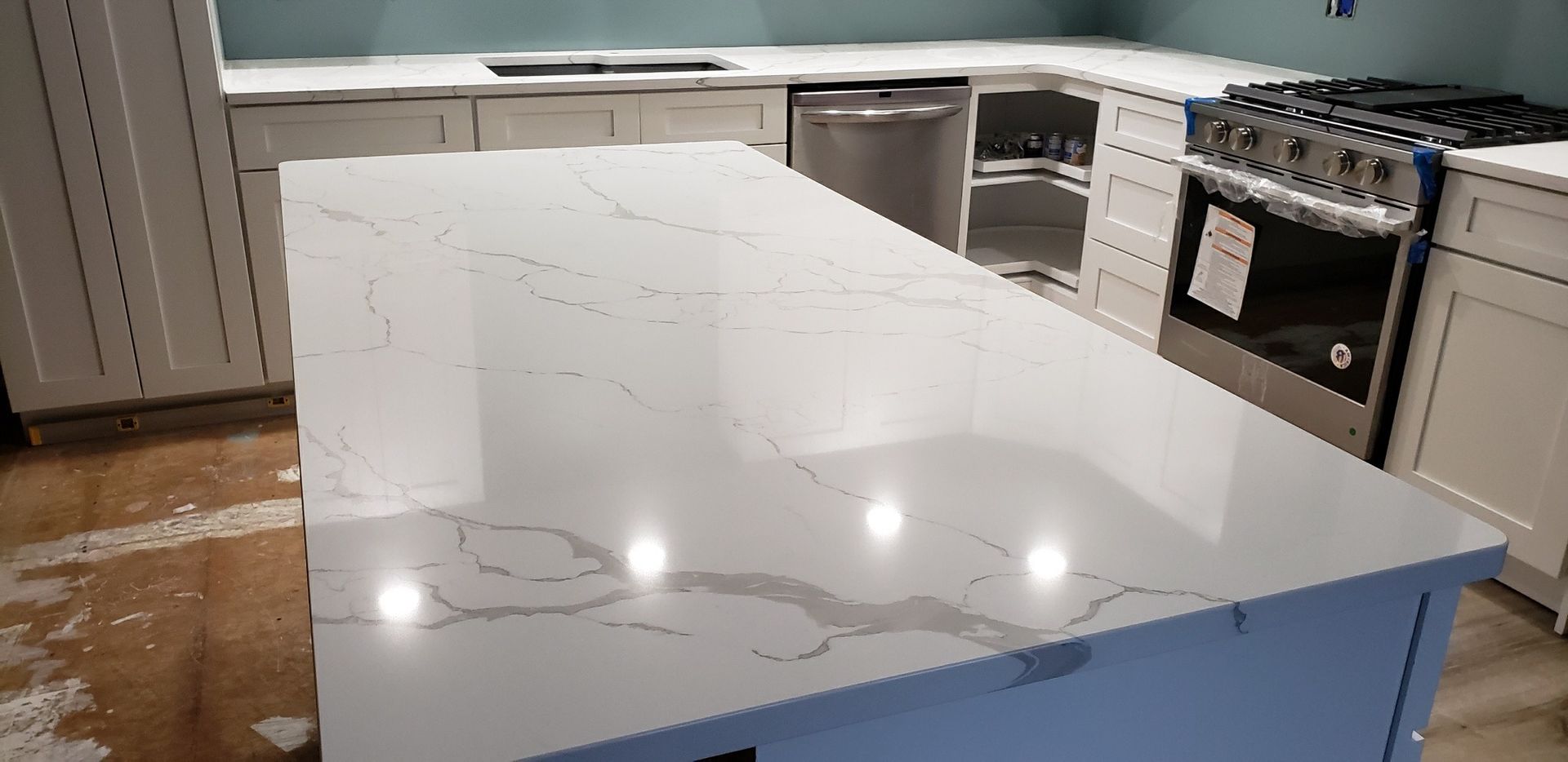 Kitchen with white cabinets, light-colored countertops, stainless steel appliances, and an island.