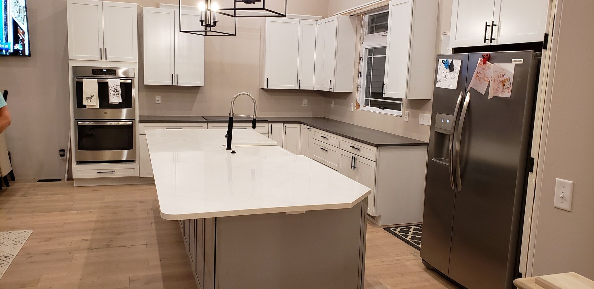 Modern white kitchen with island, cabinets, appliances, and hardwood floors.