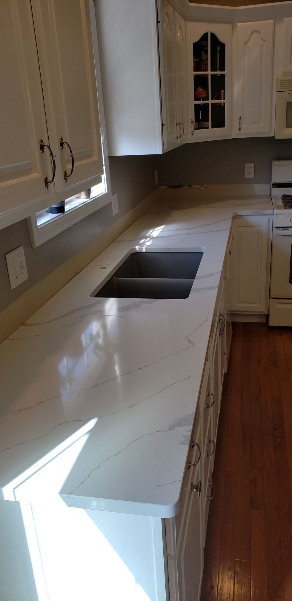 A kitchen with white cabinets, a light countertop, and a stainless steel sink.