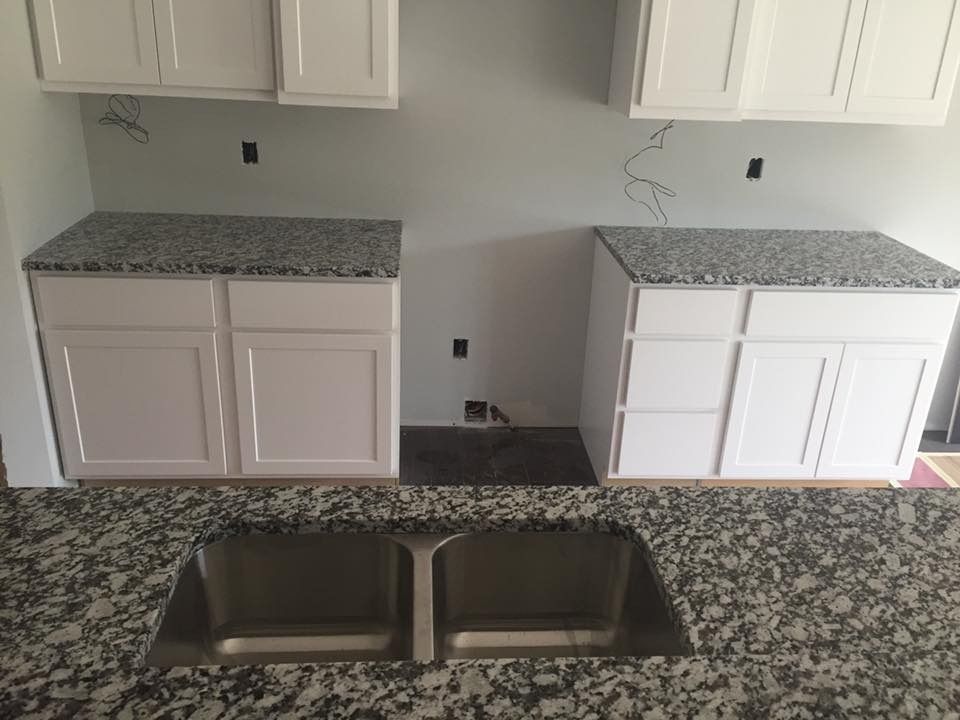 Kitchen with white cabinets, granite countertops, and a double sink.