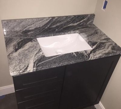 Dark vanity cabinet with granite countertop and white rectangular sink.