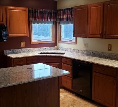 Kitchen with wooden cabinets, granite countertops, and two windows with a valance.