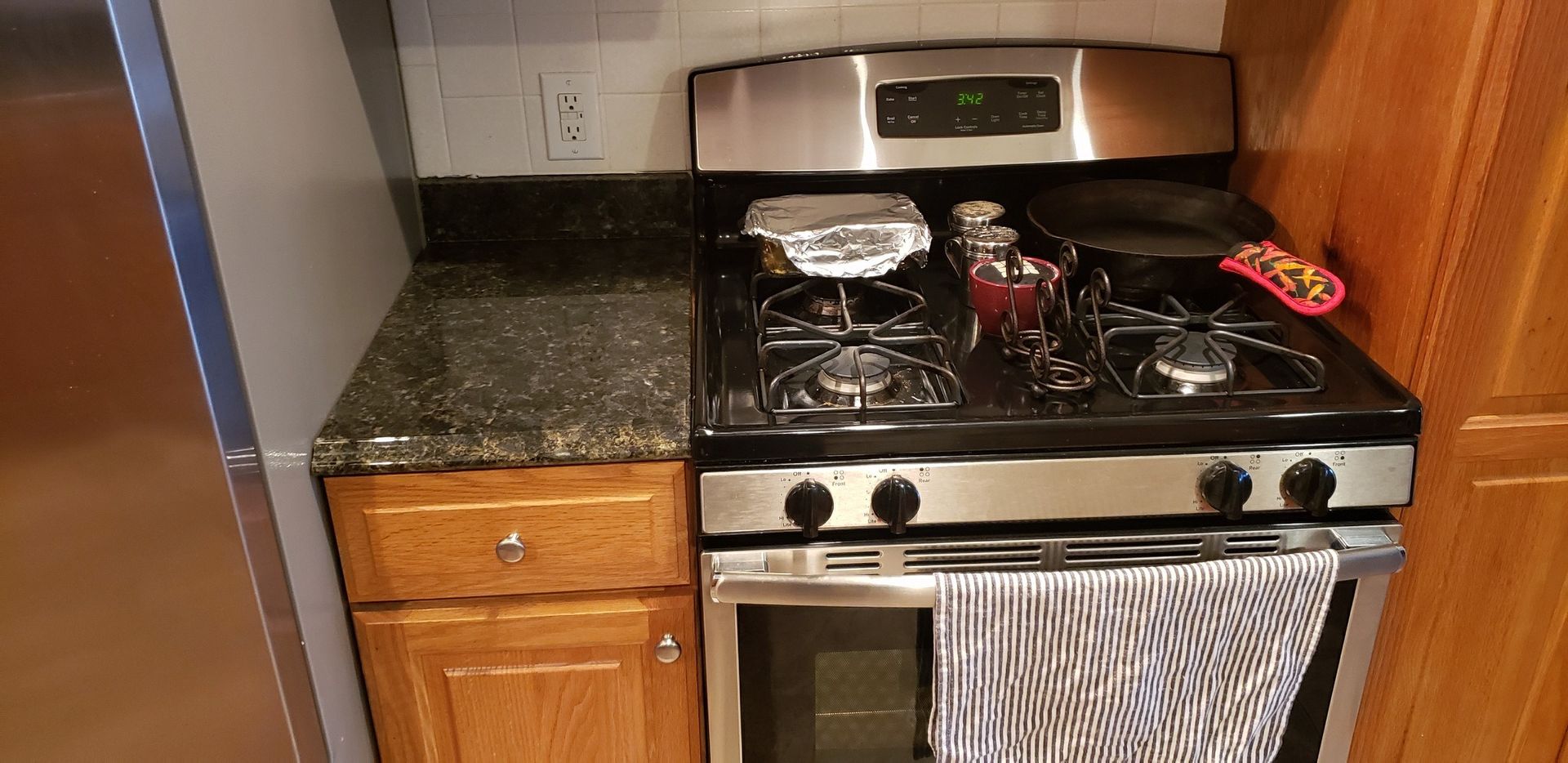 Kitchen with a stainless steel stove, granite countertop, and wooden cabinets.