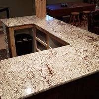 Granite countertop on a dark wood bar with a trash receptacle.