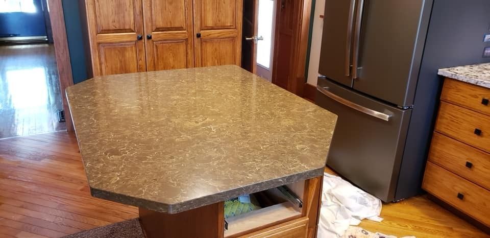 Kitchen with a brown island and cabinets, a stainless steel refrigerator, and hardwood floors.