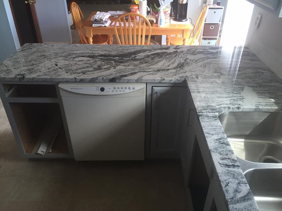 Kitchen countertop with a dishwasher, sink, and gray cabinets. Granite countertop.