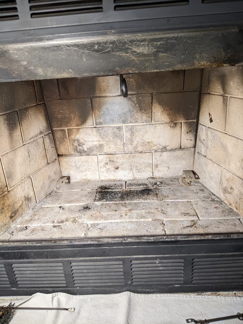 Fireplace interior with gray brick and soot.