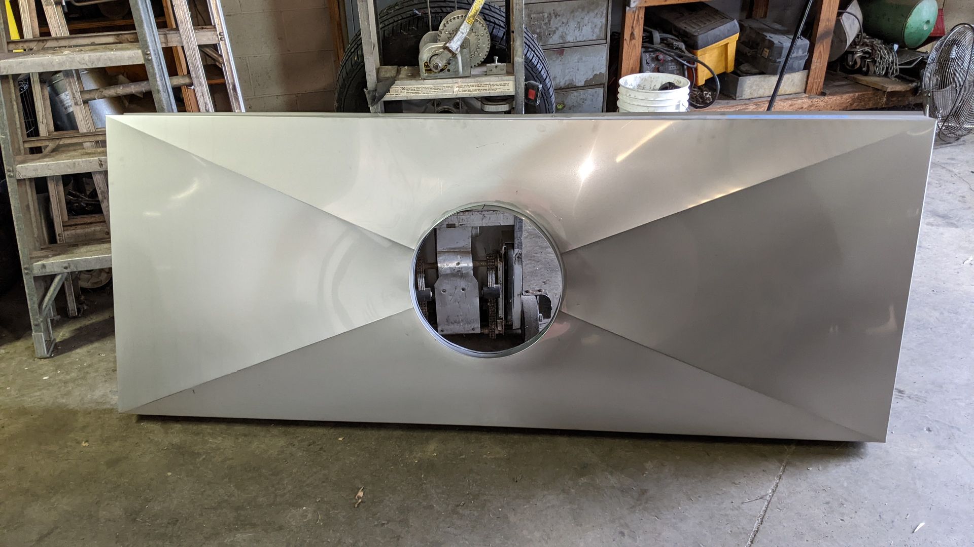 Silver metal sheet with a central circular opening, folded edges.