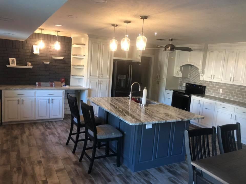 A kitchen with white cabinets and a large island in the middle.