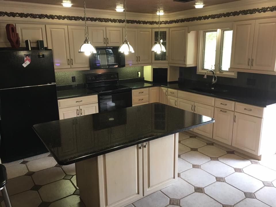A kitchen with white cabinets and black counter tops